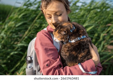 Grumpy curious cat frowns while inspecting grass nature from woman owner arms. Feline curious and cautious exploration, animal comfort zone dependence, reluctant adventurer feel discomfort and stress