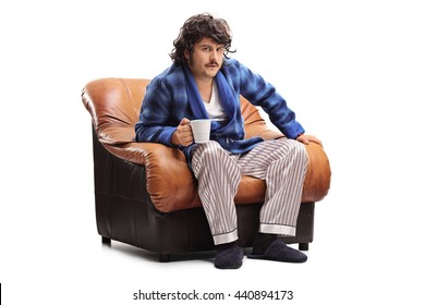 Grumpy Man Sitting In An Armchair And Drinking His Morning Coffee Isolated On White Background