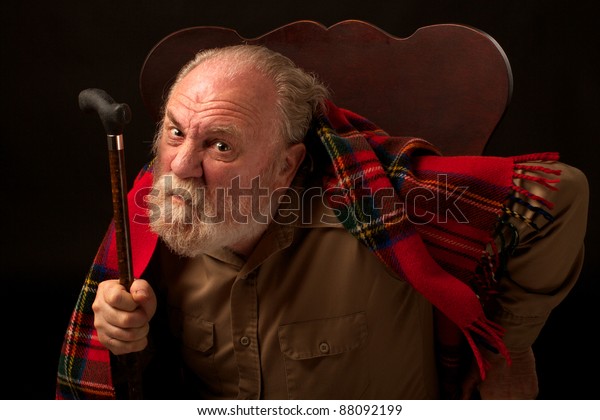 Grumpy old man shakes cane\
and frowns