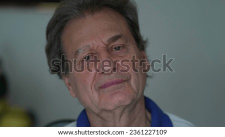 Grumpy senior man close-up face looking at camera with upset pensive expression