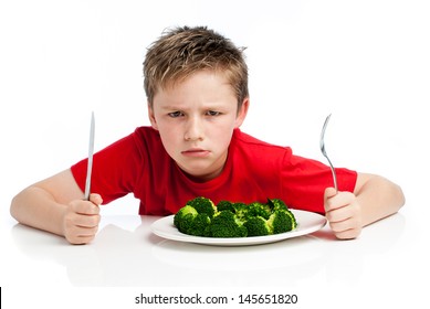 Grumpy young boy with plate of broccoli. Isolated on white background.
