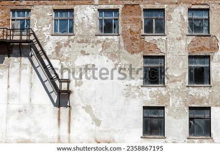 Grunge architecture details. Old abandoned factory with metal staircase and broken windows
