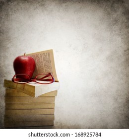 Grunge background with stack of books, apple and eyeglasses