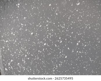 Grunge grey wall texture with random white paint splatter. Artistic abstract background with speckled pattern on a rough cement surface.
