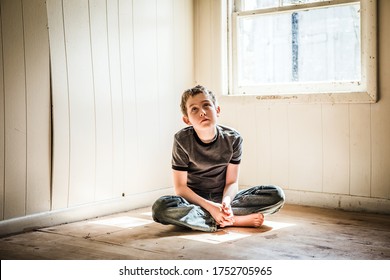 Grunge Image Of A Sad Boy Sitting Alone In An Empty Room Looking Up, Noise Added For Effect