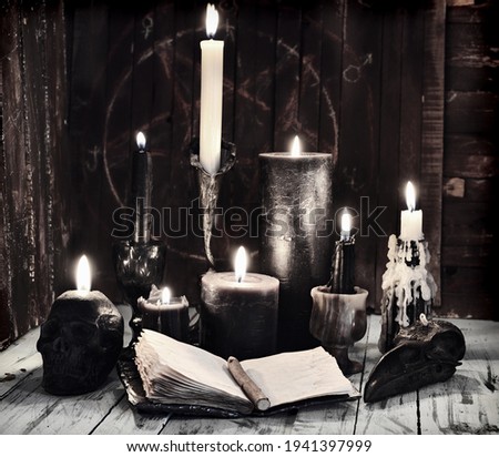 Grunge still life with burning candles and open diary book on witch table.  Esoteric, gothic and occult background, Halloween mystic concept.