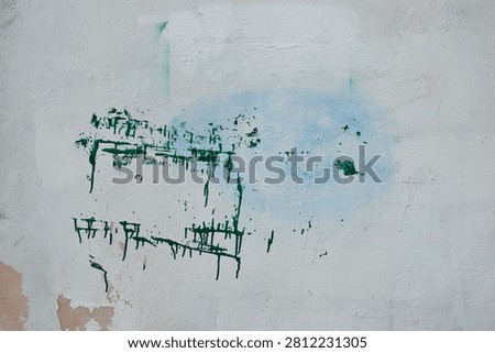 Grunge texture — a wall surface covered in white paint with drips and splotches of green, beige, and blue paint