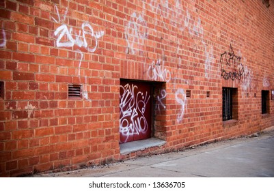 Grunge Urban Lane With Red Brick Wall And Graffiti