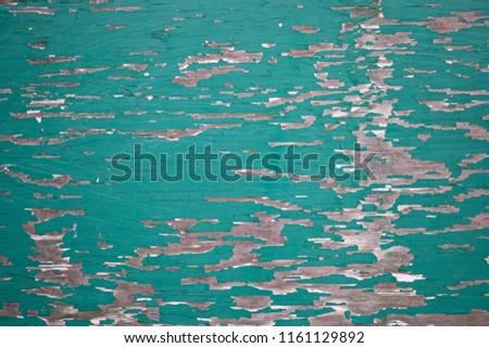 Grungy closeup of peeling flaking green paint on plywood wallpaper background