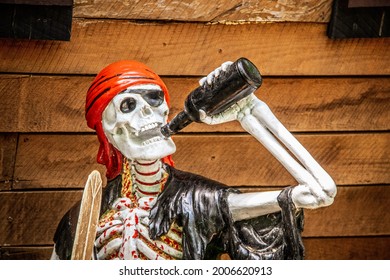 Grungy painted and glued together bloody skeleton pirate drinking beer with boat hull background Halloween decoration - closeup