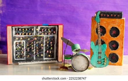 Grungy paper models of a synthesizer, drum kit, bass guitar and amplifier, free copy space
