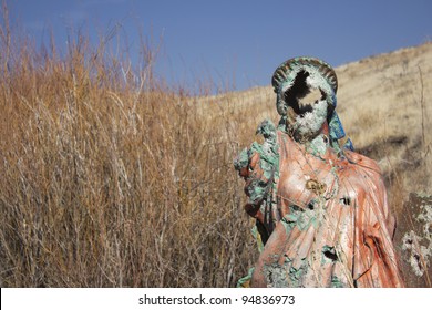 A grungy religious statue in teh middle of nowhere.