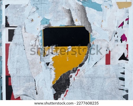 Grungy street wall with tattered ripped street posters and exposed sign 