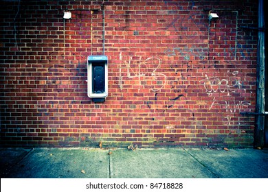 Grungy urban background of a brick wall with an old out of service payphone on it - Powered by Shutterstock