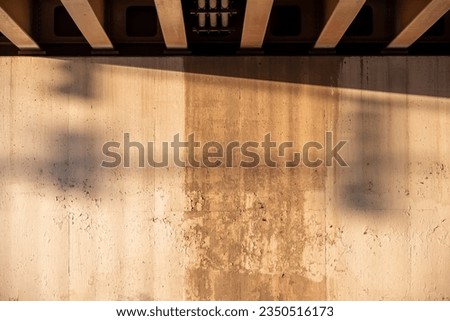 Grungy urban underpass wall with stains and peeling white paint. Shadows across empty wall space.