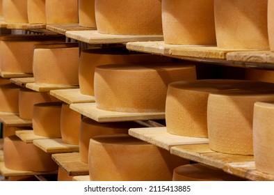 Gruyere Cheese Wheels Stacked On Wooden Shelves