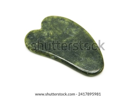 Gua Sha massager isolated on white background. Green jade stone for face and body care. Copy space. Top view.