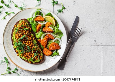 Guacamole toast with crispy chickpeas and fresh green salad with baked sweet potatoes, top view, copy space. Vegan food concept. - Powered by Shutterstock