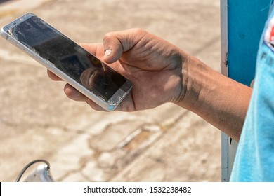 Guadalajara, Mexico - October 14 2019:  Young callous male hand holding aged, dirty smartphone  