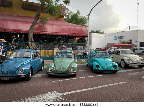 Guadalajara,\
Mexico - October 19 2019: Four VW beetle vehicles in color shades\
of blue, turquoise green and off white parked on chapultepec\
avenue. VW national convention. VW\
beetles