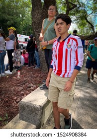 Guadalajara, Mexico - October 6 2019: Young Teenage Boy Wearing Chivas Soccer Jersey Watching An Accident Down The Road With Concerned Expression