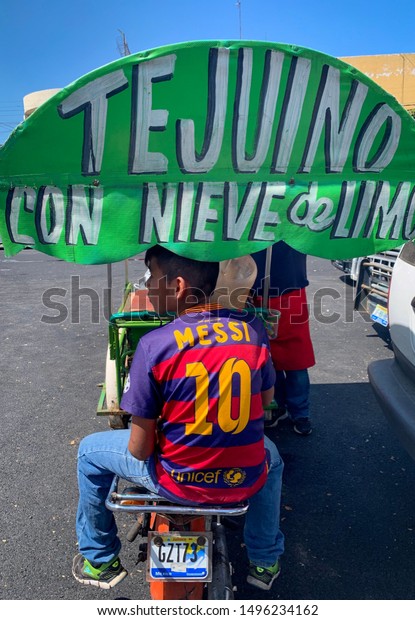 Guadalajara, Mexico -\
September 1 2019: A child wearing a Messi 10 jersey tshirt top sits\
on a Tejuino street vendor cart. Tejuino with lemon sorbet ice\
cream. Family\
business