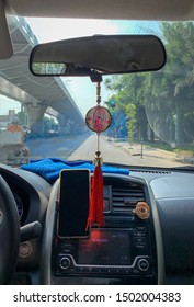 Guadalajara, Mexico - September 10 2019: Uber Driver With Lady Of Guadalupe Ornament Hanging From Rear View Mirror. Unfinished Tren Ligero Linea 3 On The Left