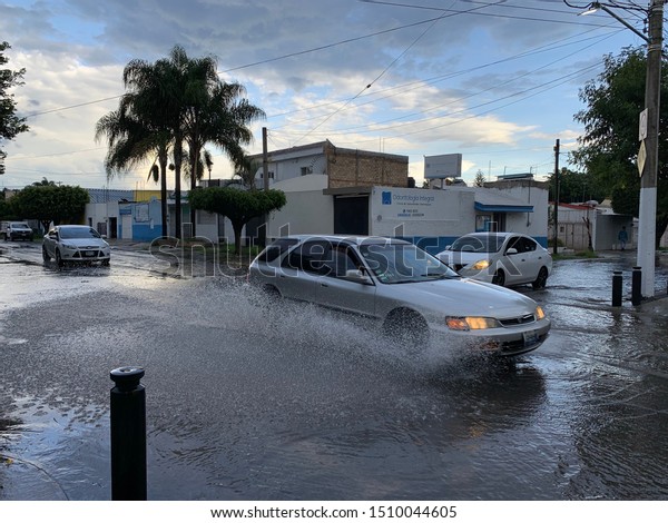Guadalajara, Mexico - September 20 2019: Car\
drives through a flooded street after heavy rain splashing rain\
water in Guadalajara in the\
afternoon