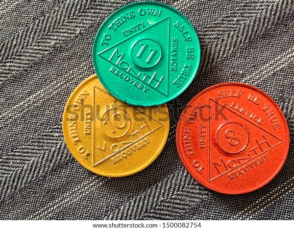 Guadalajara, Mexico - September 9 2019: AA Sobriety\
chips awarded abstaining from alcohol or other substance for for 8,\
10 and 11 months. It is a token given to 12 step group members.\
Successful rehab