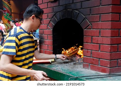 Guan Di Chinese Taoist Temple.  Man Burning Joss Paper Offerings In Kiln.  Kuala Lumpur. Malaysia.  12-20-2019