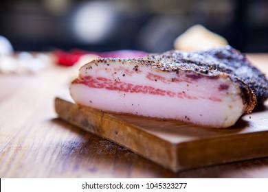 Guanciale, cured meat product prepared from pork jowl, Italian Food .Section of a Rustic Italian Bacon on wooden plate. Guanciale, spiced bacon of Italian Cuisine