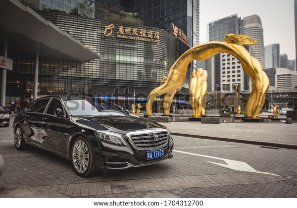 Guangzhou, China. Year 2019:\
Mercedes Benz S-Class Maybach in Guangzhou International Financial\
Center. Black luxury car and golden sculpture in gray\
day.
