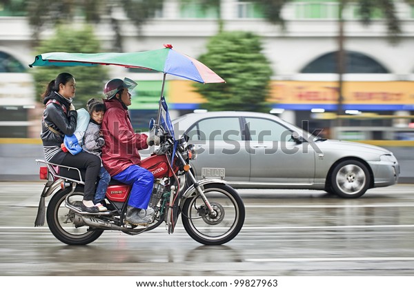GUANGZHOU-FEB. 25, 2012. Honda motorcycle taxi in\
the rain on Feb. 25, 2012 in Guangzhou. Honda was founded at 24\
September 1948 and has been the world\'s largest motorcycle\
manufacturer since\
1959.