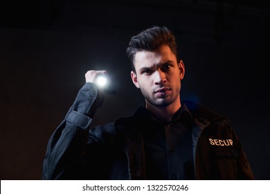 Guard In Uniform Holding Flashlight And Looking At Camera 