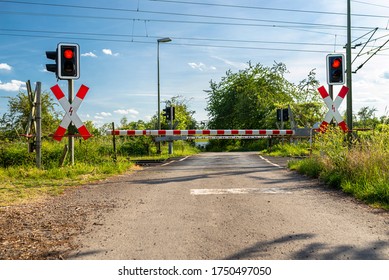 Guarded railroad crossing with closed barriers, red warning light and cross of Saint Andrew.