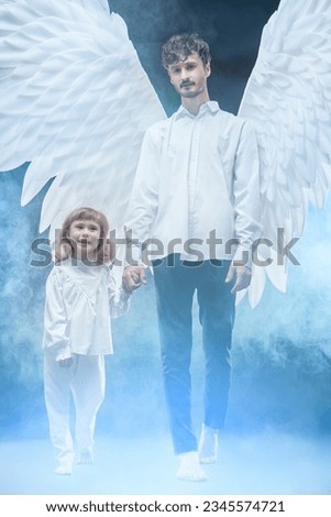 The guardian angel holds the hand of a small child, a girl in white clothes, protecting her.