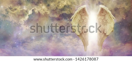 Guardian Angel Light Being Watching Over You - pair of golden Angel Wings with a bright light between against a colourful turbulent cloudscape with copy space
