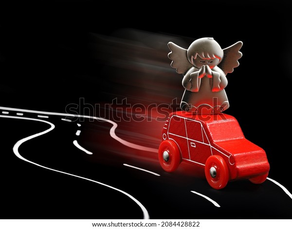 Guardian angel protects red\
car in road traffic, concept image on black background with copy\
space