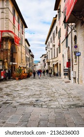 Gubbio, Italy - 21-05-2017: Beautiful Street Of The Old Italian City Which Is A UNESCO Heritage. A Participant In A Traditional Festival In A Colorful Costume Walks Along It.