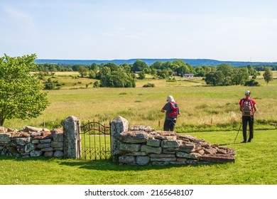 Gudhem, Sweden, July, 2021,  Hikers By An Old Iron Gate Looking At The Landscape View