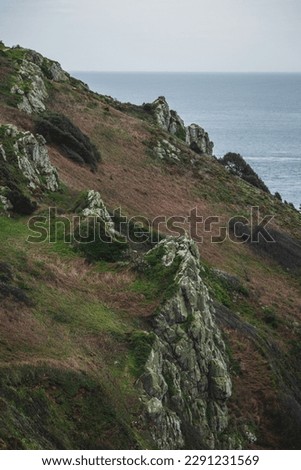 Guernsey coastal path view of craggy rocks at the top of a cliff on the island's beautiful south coast. 