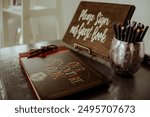 Guest book table setup with a sign reading "Please sign our guest book," a decorative pen holder, and a guest book. Ideal for themes of weddings, events, and celebrations