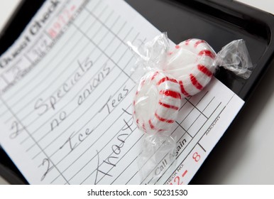 A Guest Check On A Black Tray With Red And White Mints