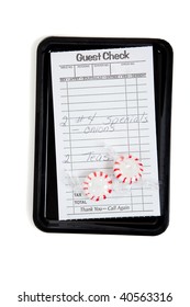 A Guest Check On A Tip Tray With Mints On A White Background