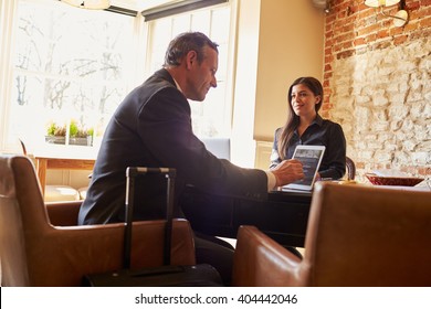 Guest Checking In At Hotel Reception Using Tablet Computer