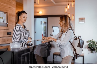 A guest is checking in at the hotel reception while the receptionist provides assistance and information. The setting is bright and welcoming.