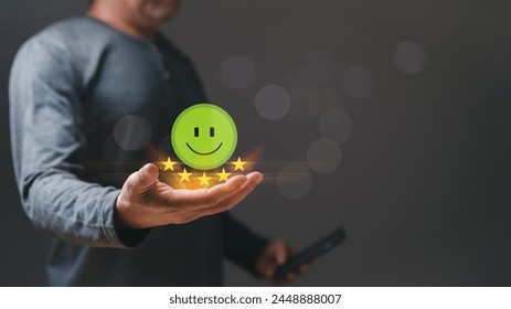 Guest or customer holding a phone with a green smile face and five stars. conveys positive and happy mood, suggesting that the person is receiving good news or has just received positive review - Powered by Shutterstock