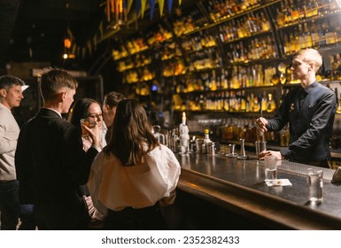 Guest drink and talk standing at bar counter and bartender takes orders in club. People enjoy party atmosphere in contemporary pub - Powered by Shutterstock