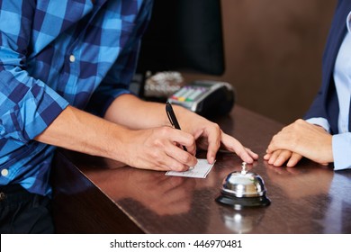 Guest At Hotel Reception Paying With Check During Check-in