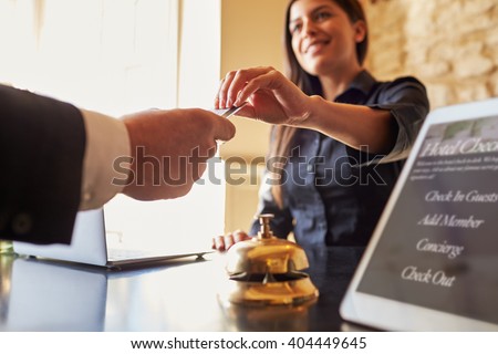 Guest takes room key card at check-in desk of hotel, close up